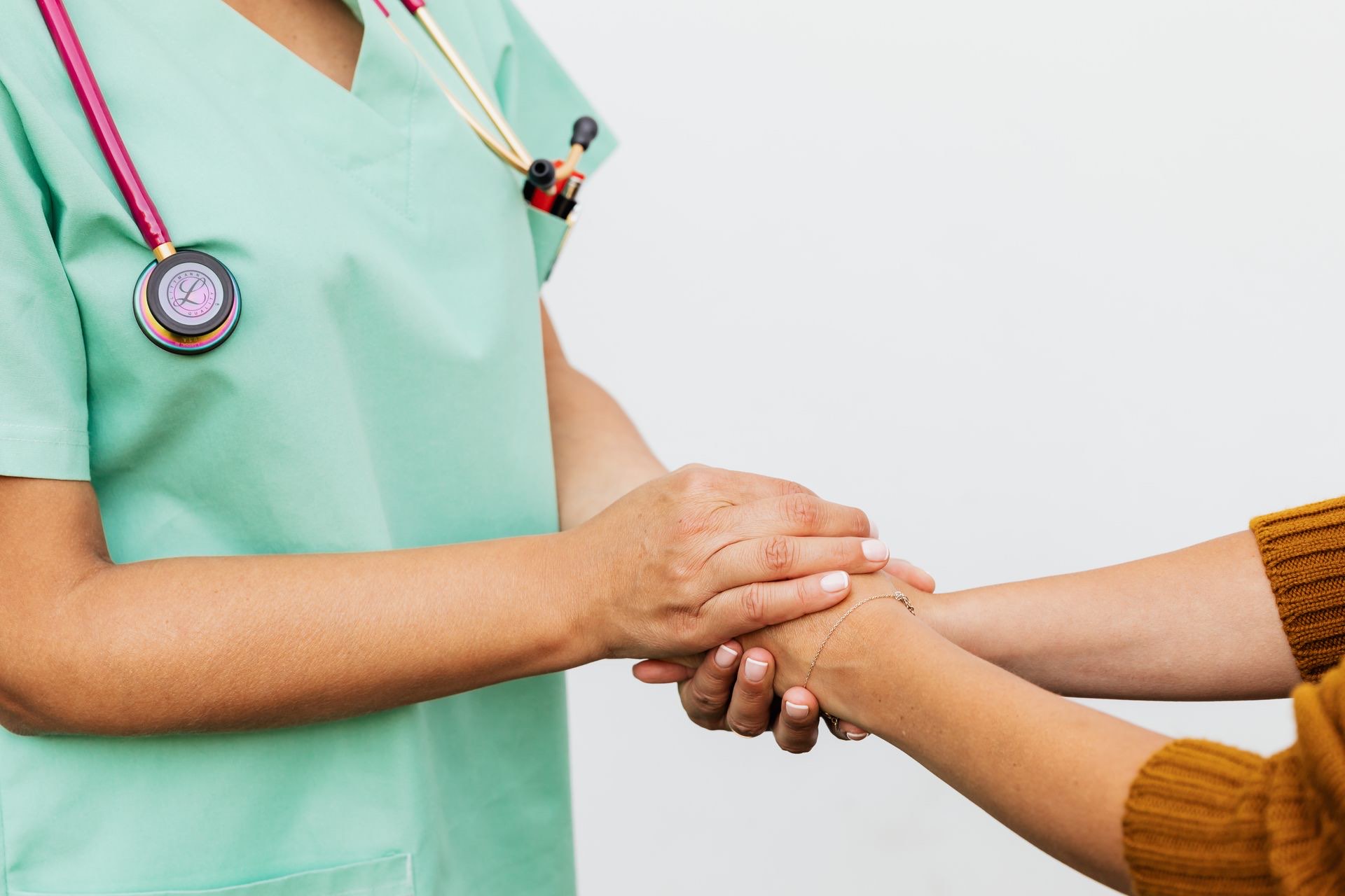 A clinician compassionately holding a patient's hand